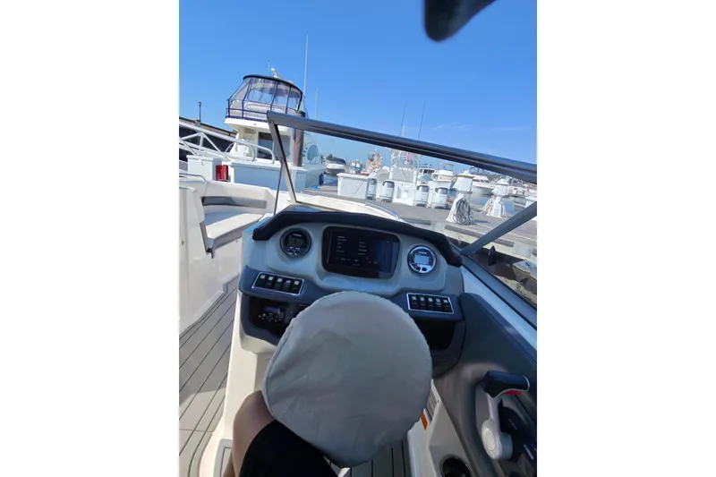 Slide: The Image of 2018 Chaparral 230 Suncoast boat dashboard view at marina, clear blue sky. - 13