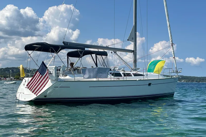 The Image of 2005 Jeanneau Sun Odyssey 40.3 sailboat on calm water, with flags and clear skies. - 0