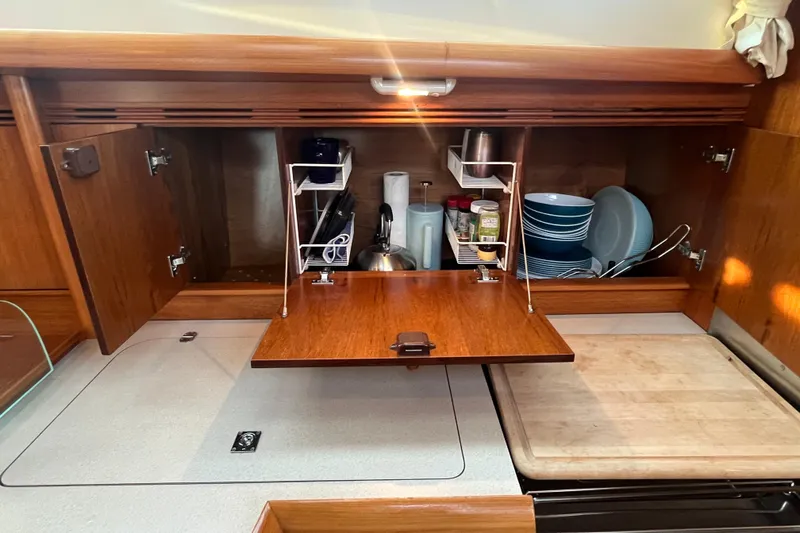 Slide: The Image of Galley of 2005 Jeanneau Sun Odyssey 40.3 with open wooden cabinets and kitchenware. - 43