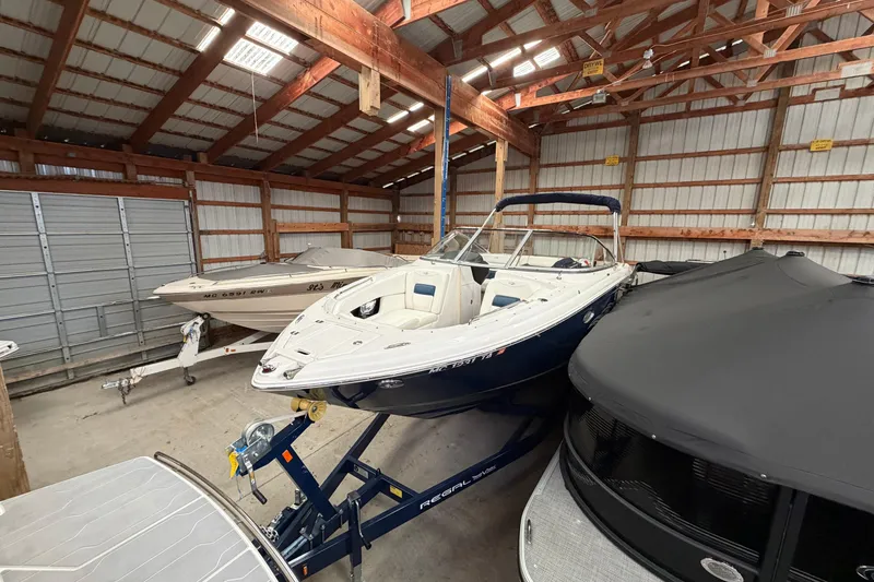 Slide: The Image of 2008 Regal 2700 Bowrider boat stored in a wooden garage with other boats. - 8
