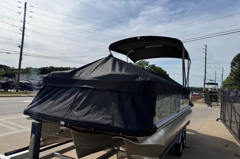 Slide: The Image of 2026 Avalon VENTURE QUAD LOUNGE pontoon boat with cover on trailer, parked outdoors. - 101