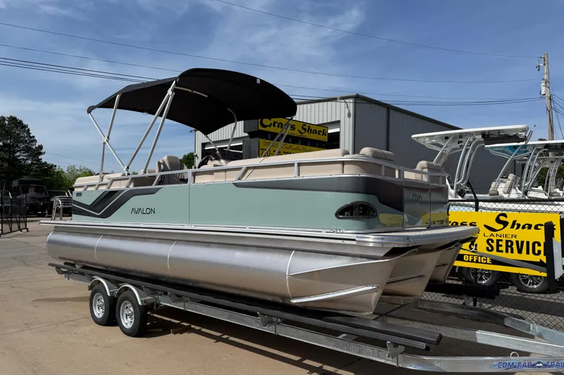The Image of 2026 Avalon VENTURE QUAD LOUNGE pontoon boat on trailer, outdoor dealership setting. - 55