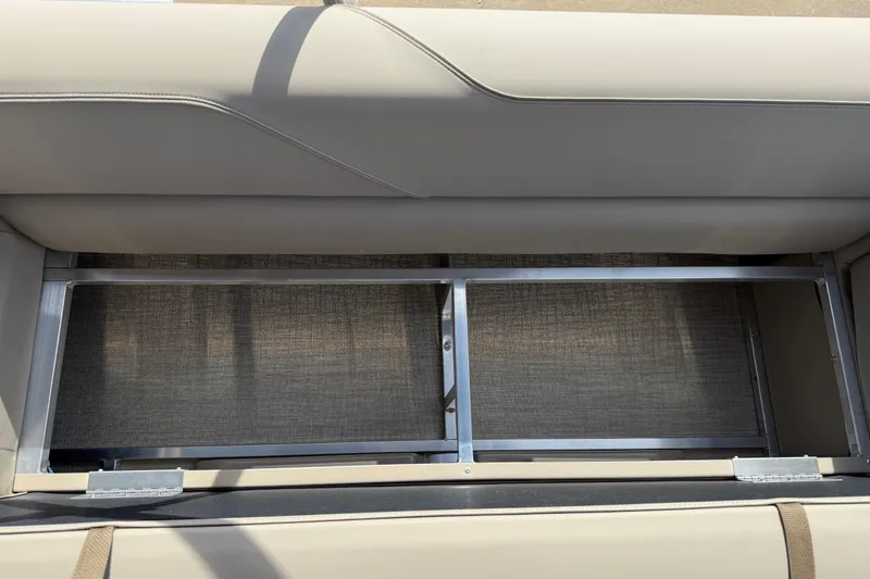 Slide: The Image of 2026 Avalon VENTURE QUAD LOUNGE seat storage compartment with metal frame and beige upholstery. - 96