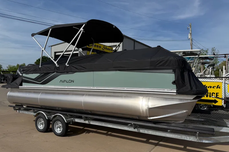 Slide: The Image of 2026 Avalon VENTURE QUAD LOUNGE pontoon boat on trailer, covered and parked outdoors. - 97