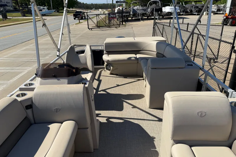 Slide: The Image of 2022 Tahoe Pontoon Sport Cruise interior with beige seating and cup holders, docked outdoors. - 17