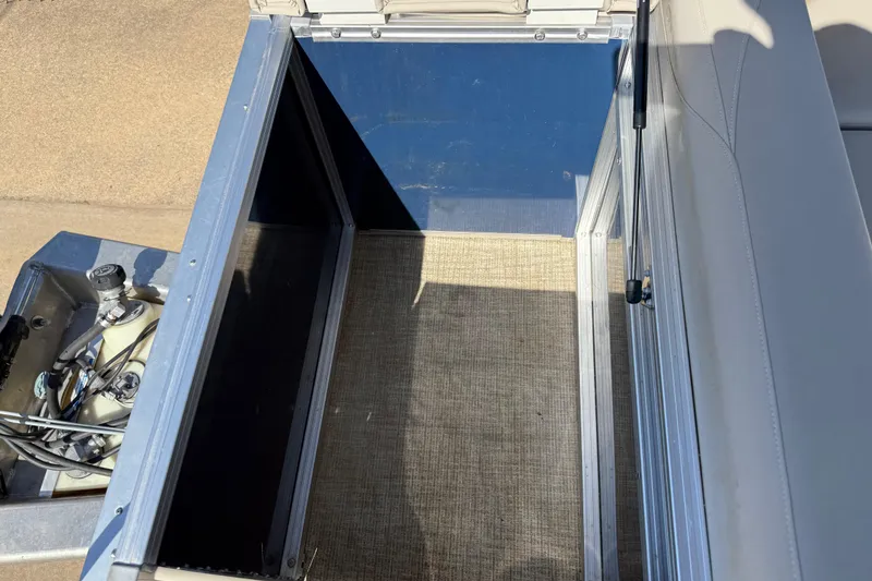 Slide: The Image of 2022 Tahoe Pontoon Sport Cruise storage compartment with hydraulic lift and carpeted interior. - 29