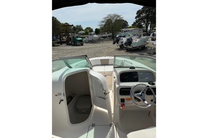Slide: The Image of 2019 Robalo R207 Dual Console boat interior with steering wheel and open cabin door. - 16