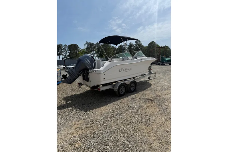 Slide: The Image of 2019 Robalo R207 Dual Console boat on trailer, parked outdoors under clear sky. - 24