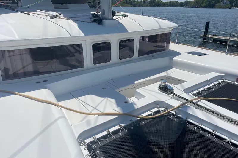 Slide: The Image of 2016 Lagoon 450 F catamaran deck with winch and netting, docked by the water. - 26