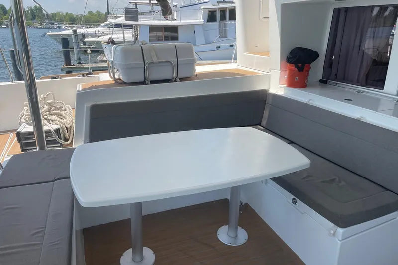 Slide: The Image of Outdoor seating area on a 2016 Lagoon 450 F catamaran, featuring a white table and gray cushions. - 27