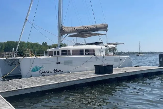 Slide: The Image of 2016 Lagoon 450 F catamaran docked, named "Sacre Bleu," under clear blue sky. - 35