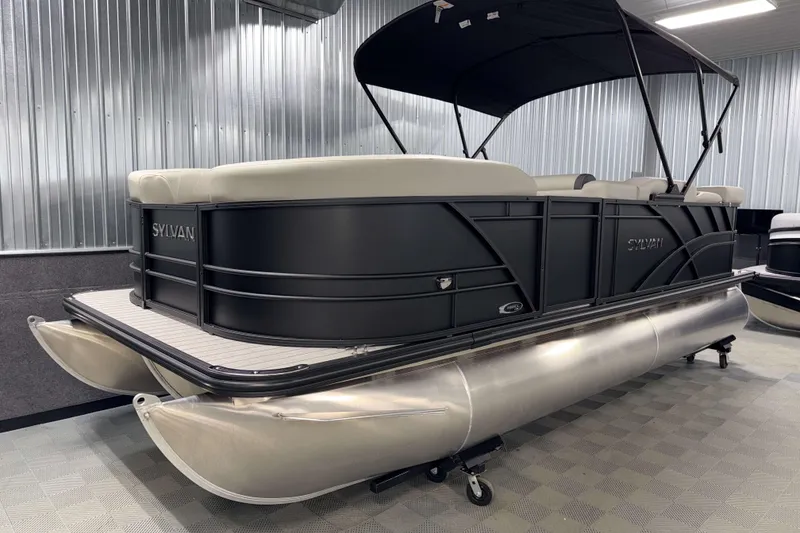 Slide: The Image of 2026 Sylvan Mirage 8520 Cruise PTS Tritoon in showroom, featuring sleek black design and canopy. - 17