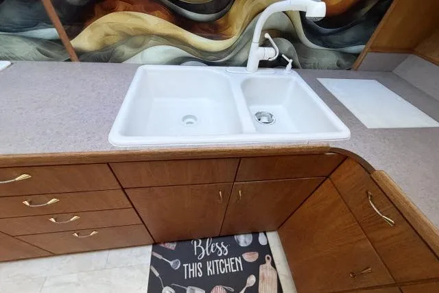 Slide: The Image of Kitchen sink area with dual basins, wooden cabinets, and decorative backsplash in a 1986 Fexas Custom 57. - 12