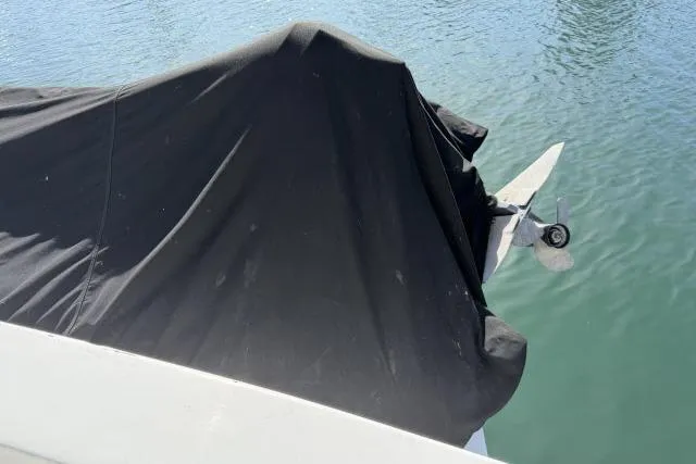 Slide: The Image of A covered 1986 Fexas Custom 57 boat docked on calm water. - 47