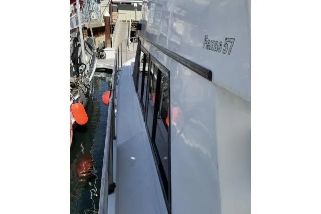 Slide: The Image of 1986 Fexas Custom 57 yacht docked, showcasing sleek design and reflective windows. - 52