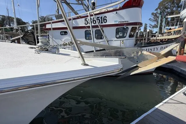 Slide: The Image of 1986 Fexas Custom 57 yacht docked near a fishing boat in a marina. - 56