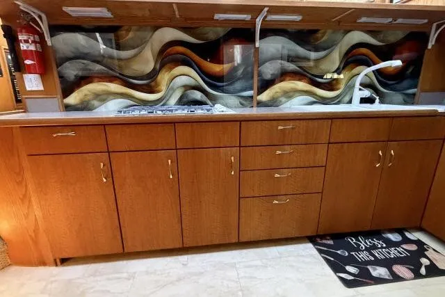 Slide: The Image of Kitchen area of a 1986 Fexas Custom 57 with wooden cabinets and a wavy backsplash design. - 9