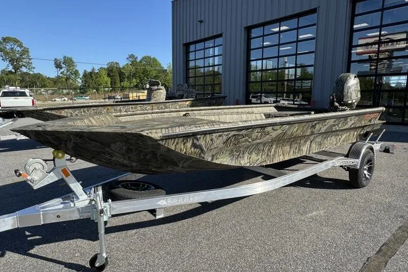 The Image of 2026 SeaArk 1960 Slayer Pro boat on trailer, parked outside a building. - 1