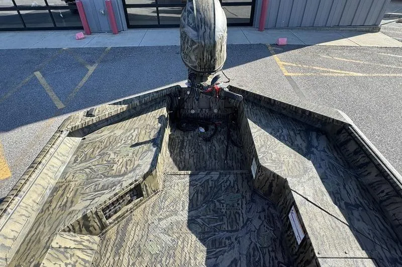 Slide: The Image of 2026 SeaArk 1960 Slayer Pro boat with camouflage design, parked outdoors. - 12