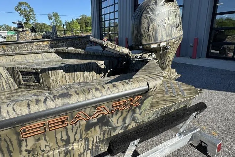 Slide: The Image of 2026 SeaArk 1960 Slayer Pro boat with camouflage design, parked outside a building. - 4