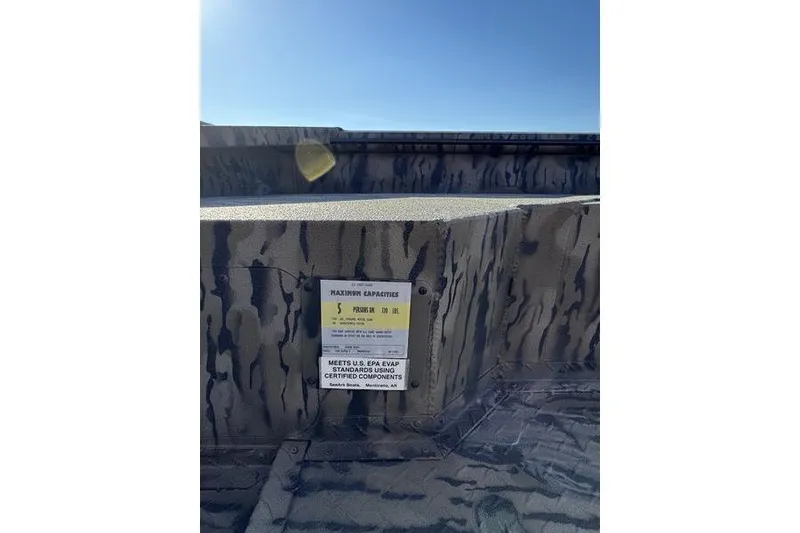 Slide: The Image of 2026 SeaArk 1960 Slayer Pro boat interior with capacity label and camouflage design. - 8