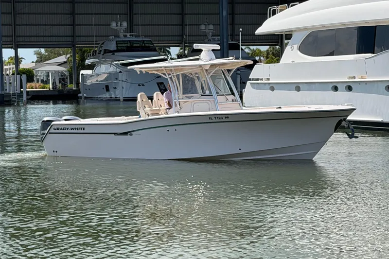 The Image of 2013 Grady-White Canyon 306 boat docked in marina, surrounded by larger yachts. - 0