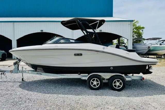 The Image of 2025 Sea Ray SPX 210 boat on trailer, parked outdoors near a blue building. - 0