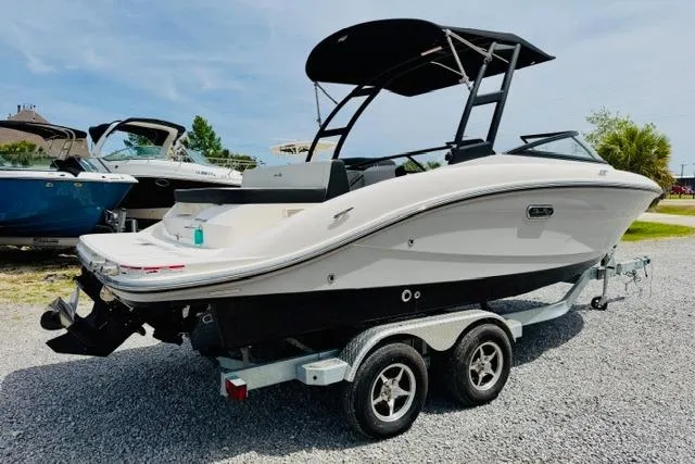 Slide: The Image of 2025 Sea Ray SPX 210 boat on trailer, parked outdoors on gravel. - 2
