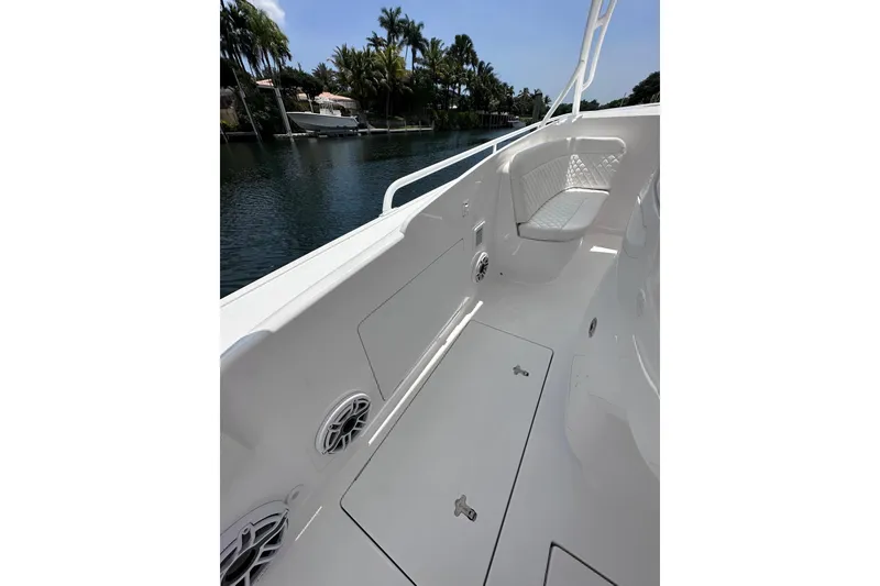 Slide: The Image of 2024 Intrepid 41 Valor boat interior with seating and storage, docked by a scenic waterway. - 26