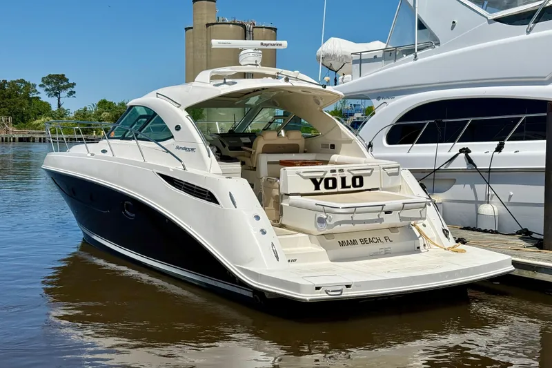 The Image of 2012 Sea Ray 410 Sundancer yacht docked, featuring sleek design and "YOLO" on the stern. - 2