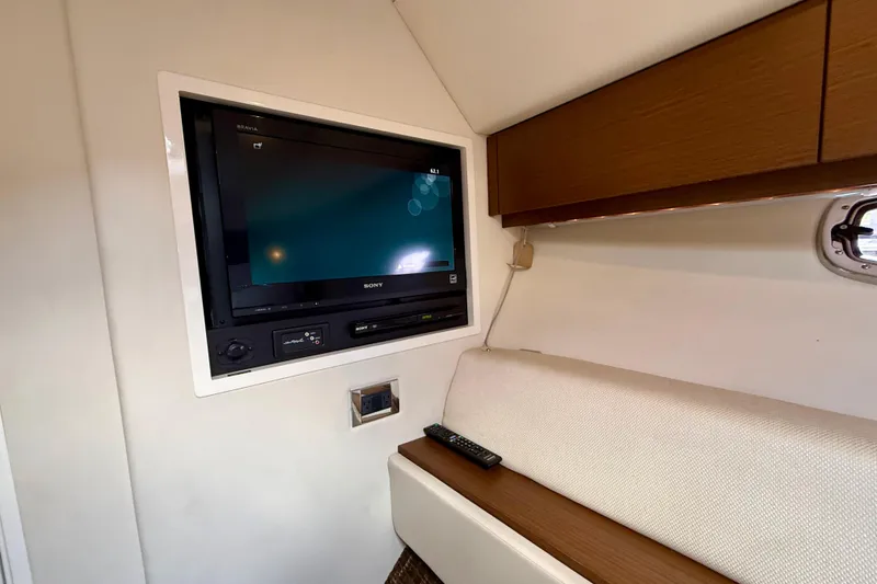 Slide: The Image of Interior of 2012 Sea Ray 410 Sundancer with wall-mounted Sony TV and remote control. - 48