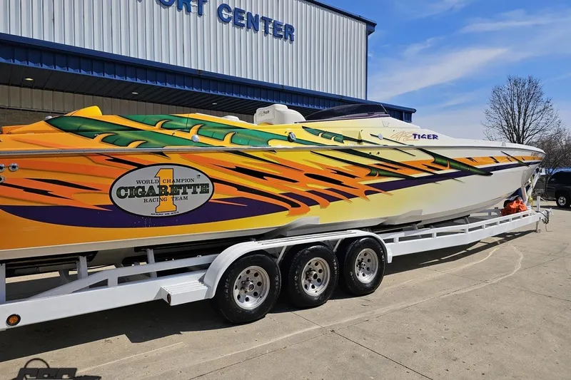 Slide: The Image of 2001 Cigarette 42' Tiger powerboat with vibrant graphics on a trailer outside a sport center. - 10