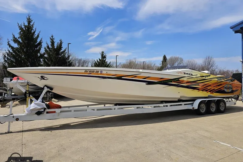 Slide: The Image of 2001 Cigarette 42' Tiger speedboat on trailer, vibrant graphics, parked outdoors. - 19