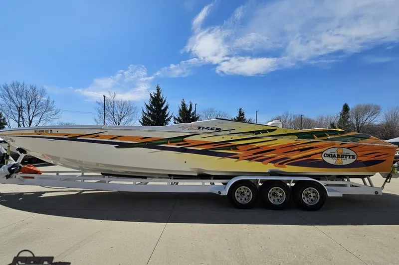 Slide: The Image of 2001 Cigarette 42' Tiger speedboat with vibrant graphics on a trailer under a clear sky. - 20