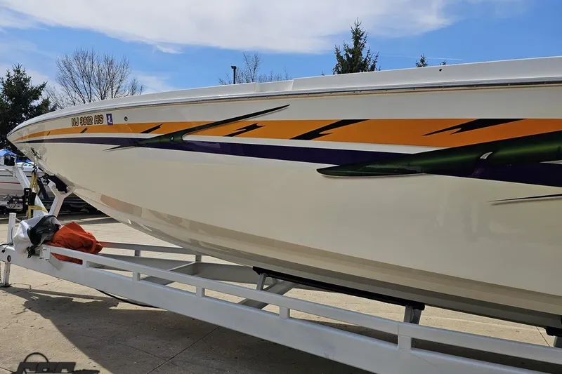 Slide: The Image of 2001 Cigarette 42' Tiger boat on trailer with vibrant graphics and clear sky background. - 21