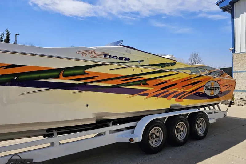 Slide: The Image of 2001 Cigarette 42' Tiger speedboat with vibrant graphics on a trailer. - 22