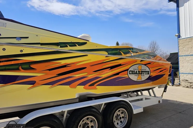 Slide: The Image of 2001 Cigarette 42' Tiger boat with vibrant flame graphics on trailer. - 23