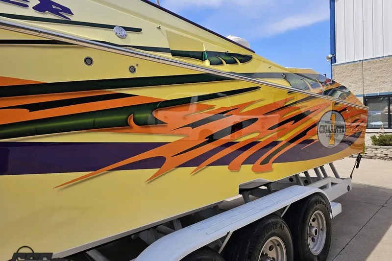 Slide: The Image of 2001 Cigarette 42' Tiger boat with vibrant orange and green graphics on trailer. - 24