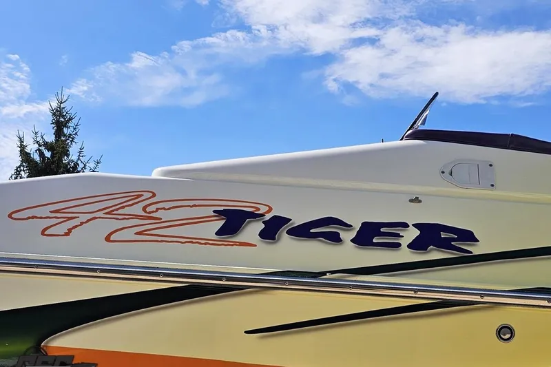 Slide: The Image of 2001 Cigarette 42' Tiger boat with vibrant graphics against a clear blue sky. - 26