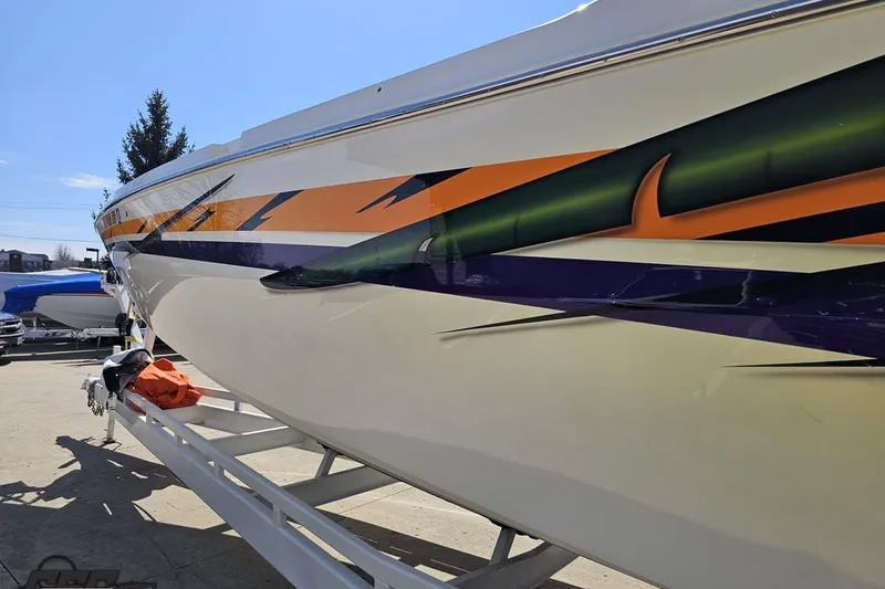 Slide: The Image of 2001 Cigarette 42' Tiger boat with vibrant orange and green graphics on trailer. - 28