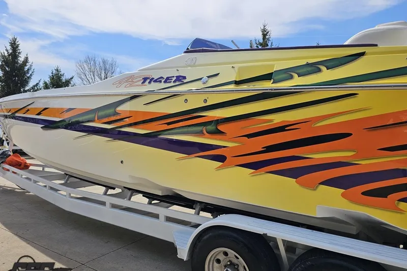 Slide: The Image of 2001 Cigarette 42' Tiger boat with vibrant custom graphics on a trailer. - 29
