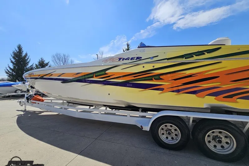 Slide: The Image of 2001 Cigarette 42' Tiger boat with vibrant graphics on a trailer under a clear sky. - 30
