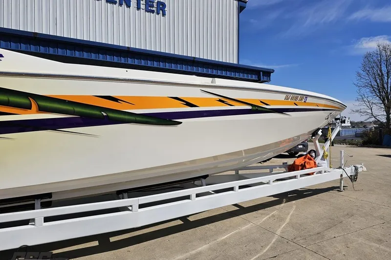 Slide: The Image of 2001 Cigarette 42' Tiger boat on trailer, vibrant graphics, parked outdoors. - 4