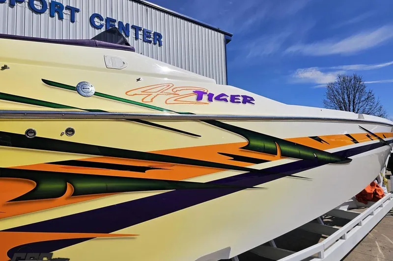 Slide: The Image of 2001 Cigarette 42' Tiger boat with vibrant graphics, displayed at a support center. - 7