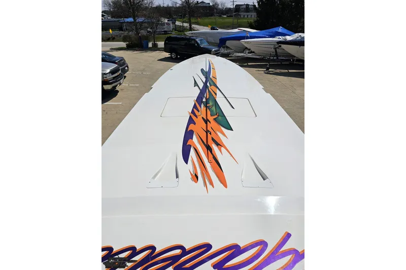 Slide: The Image of 2001 Cigarette 42' Tiger boat with vibrant graphics on deck, parked outdoors. - 76