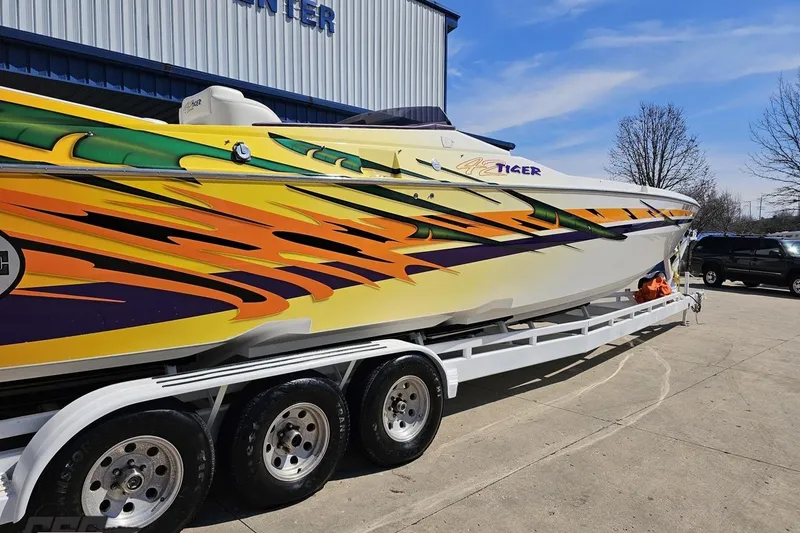 Slide: The Image of 2001 Cigarette 42' Tiger boat with vibrant flame graphics on a trailer. - 9