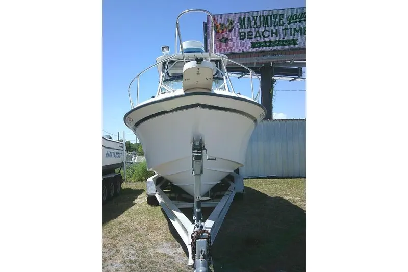 Slide: The Image of 2000 Grady-White Sailfish 272 boat on trailer, parked outdoors under a billboard. - 3