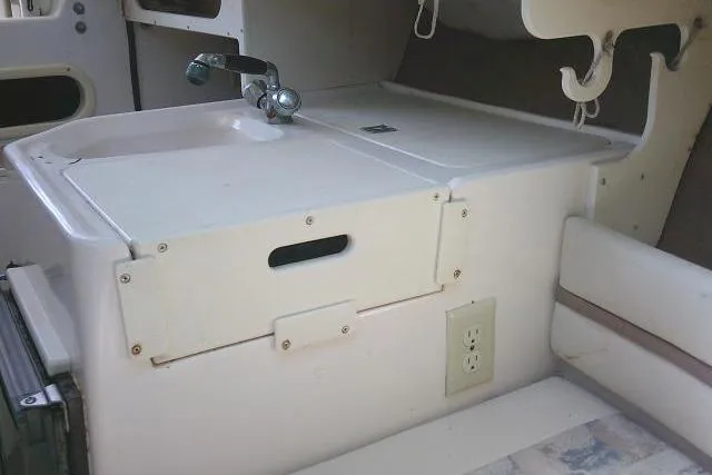 Slide: The Image of Interior view of a 2000 Grady-White Sailfish 272 boat, featuring a compact kitchenette with a sink. - 42