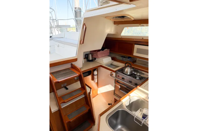 Slide: The Image of Interior of 1996 Catalina 36 MkII sailboat, featuring a compact kitchen with wooden cabinetry. - 60