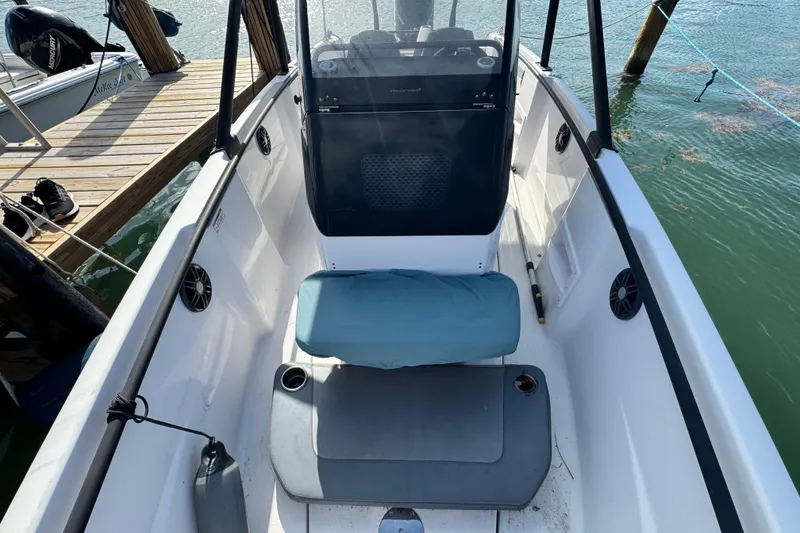 Slide: The Image of 2022 Axopar 22 T-Top boat interior with seating and console, docked by the water. - 12